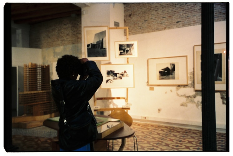 A person taking a picture of a room with pictures on the wall