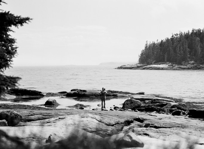 A black and white photo of a person standing on a beach