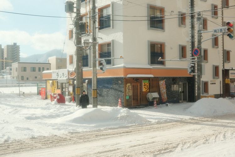 A city street covered in snow next to a tall building