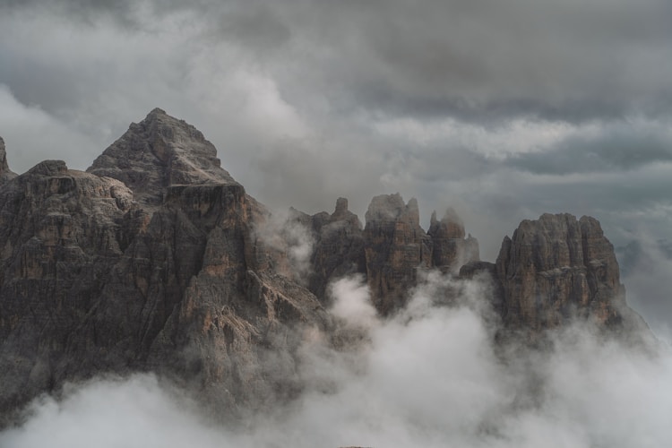 A mountain covered in clouds and fog under a cloudy sky