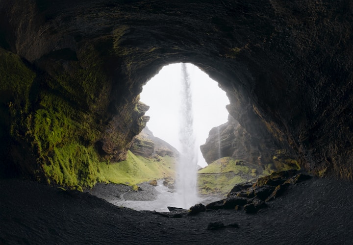 Cave entrance reveals a beautiful waterfall scene.