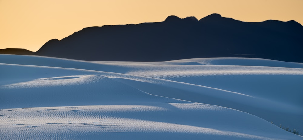 White sand dunes with a mountain silhouetted.