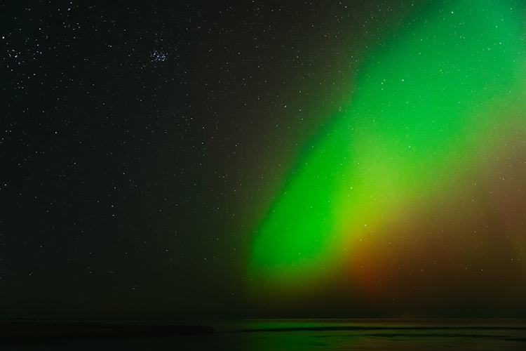 Aurora borealis glows brightly in the night sky.