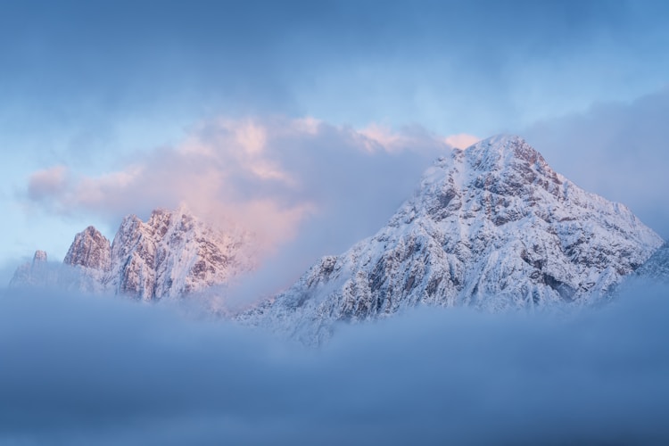 A mountain covered in snow under a cloudy sky