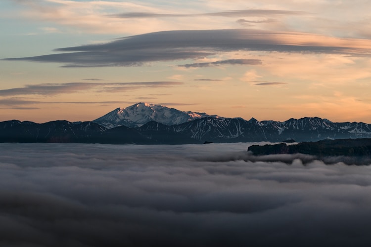 A misty landscape with snowy mountains and sky.