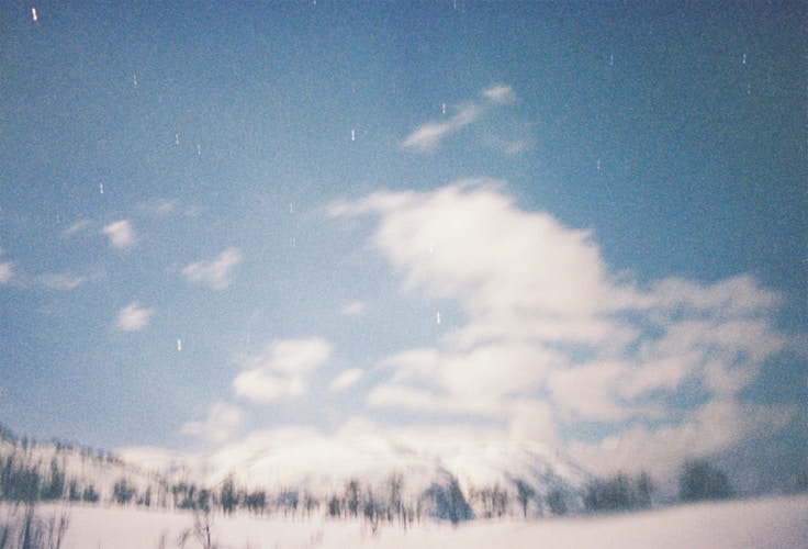 Snow-covered mountains meet a bright, cloudy sky.