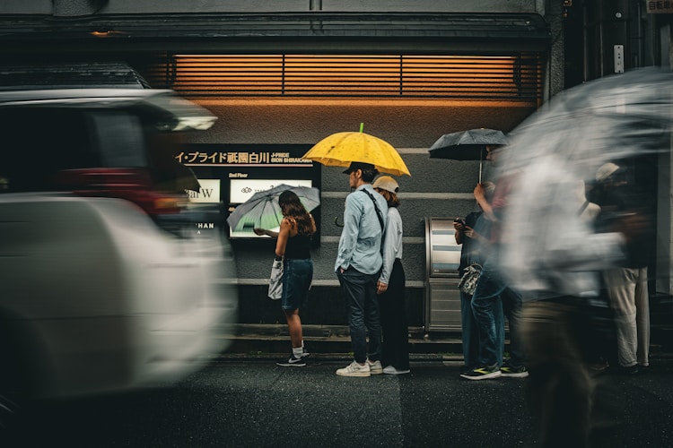 People stand under umbrellas on a rainy street.