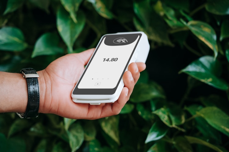A hand holds a payment terminal.