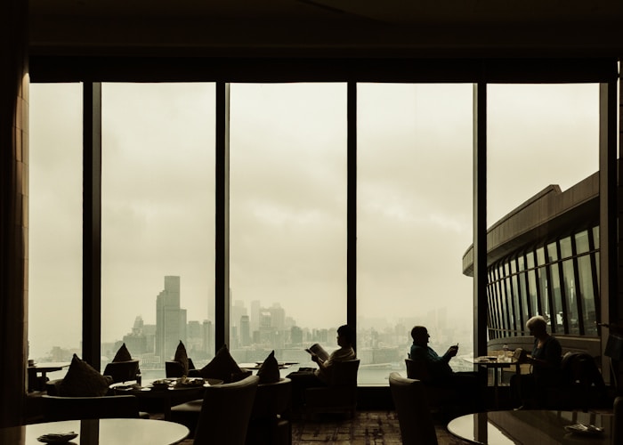 People sit near a window overlooking a cityscape.