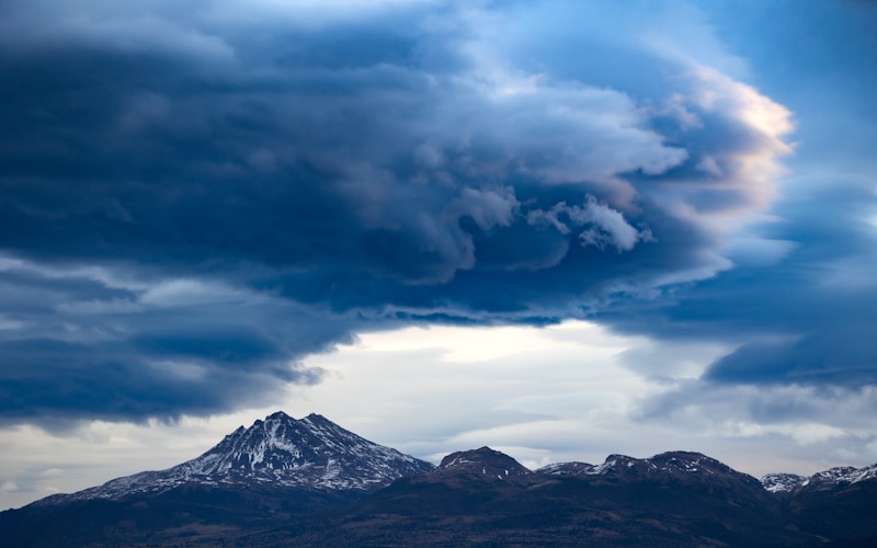 Dark clouds hover over snow-capped mountain peaks.