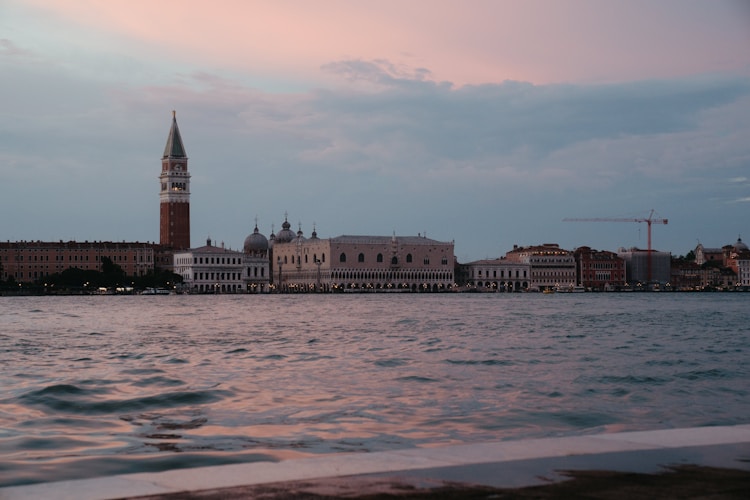 Venice cityscape at sunset reflects in the water.