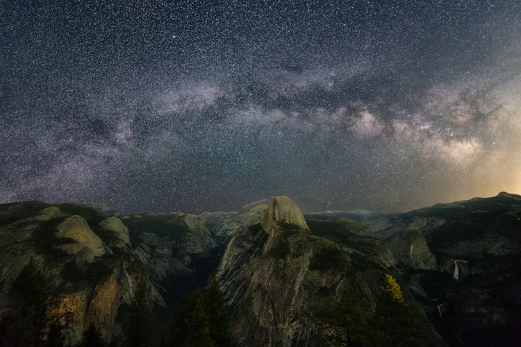 Milky way shines over mountain peaks.