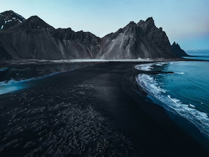 Black sand beach with imposing mountain range.