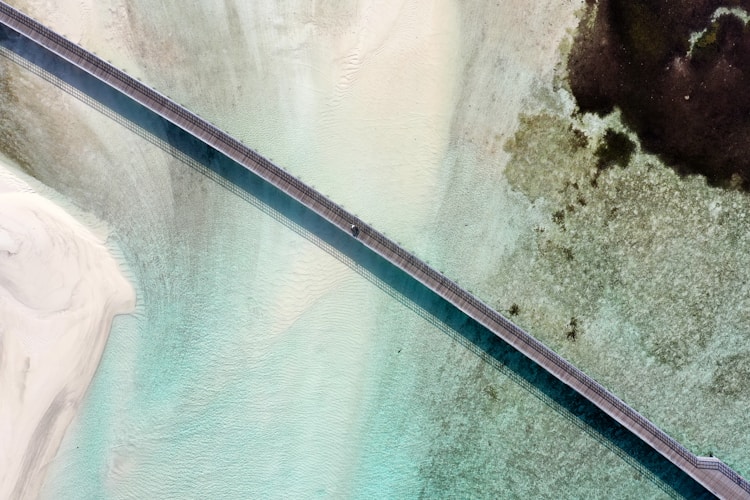 A bridge spans over crystal clear water.