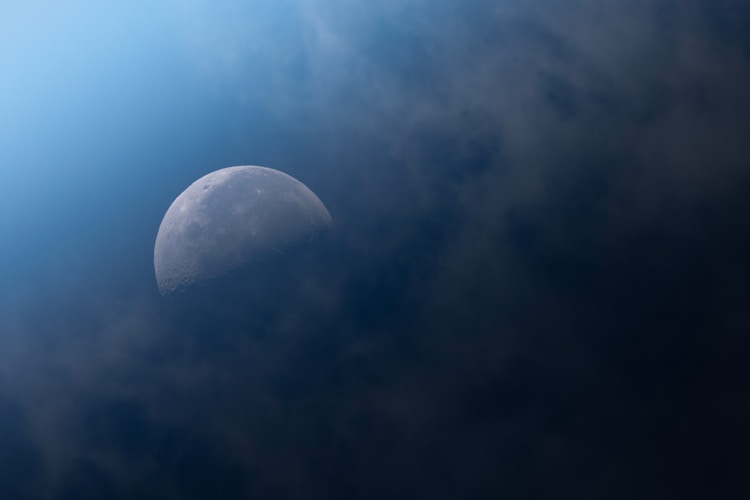 The moon peeks through dark, cloudy skies.