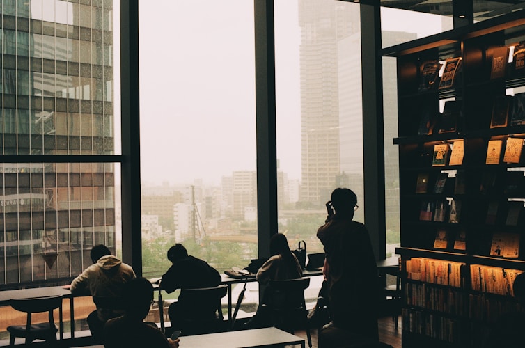 People sit and work by a large city window.