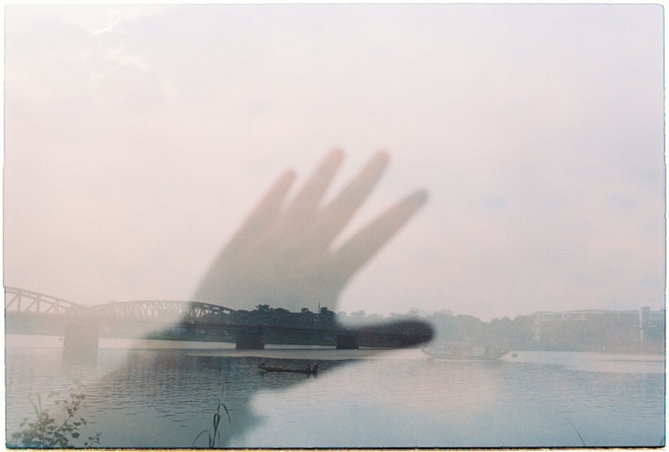 A hand appears translucent over a misty landscape.