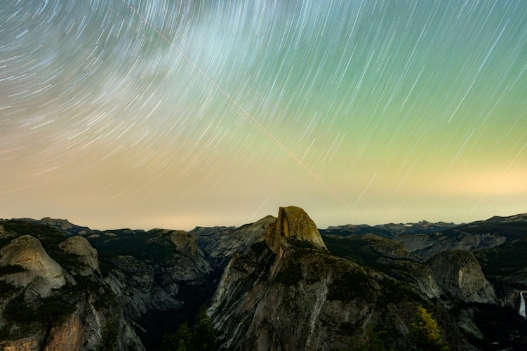 Mountains and stars illuminate the night sky.