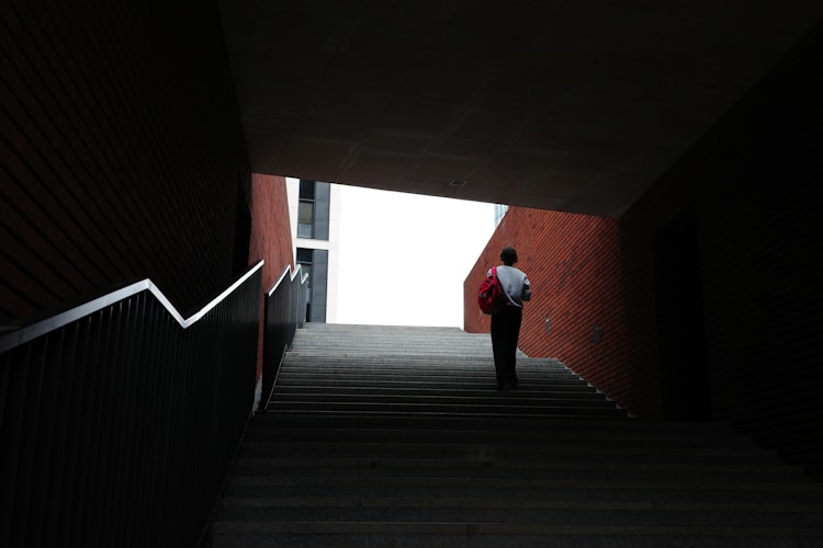 A person walks up the stairs toward the light.