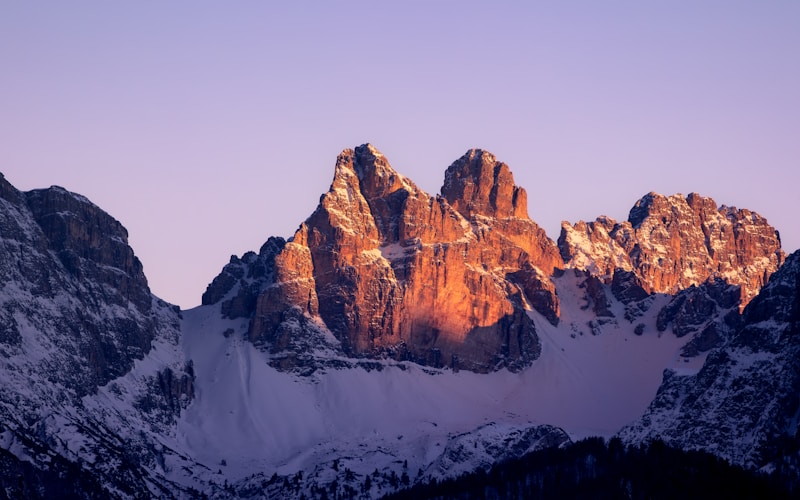 Snowy mountains are illuminated by the sunlight.