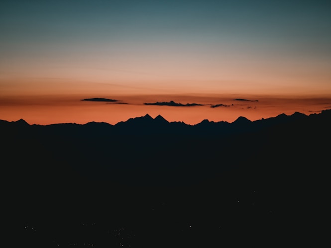 Sunset paints the sky over dark mountain silhouettes.